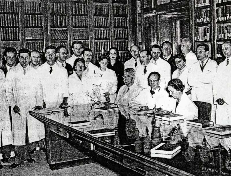 Daniel Bovet con i collaboratori nella Biblioteca del laboratorio di chimica terapeutica nel 1957. Alla sua sinistra Filomena Nitti.  [Bignami, 1993, p. 49]