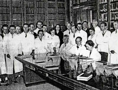 Daniel Bovet con i collaboratori nella Biblioteca del laboratorio di chimica terapeutica nel 1957. Alla sua sinistra Filomena Nitti.  [Bignami, 1993, p. 49]